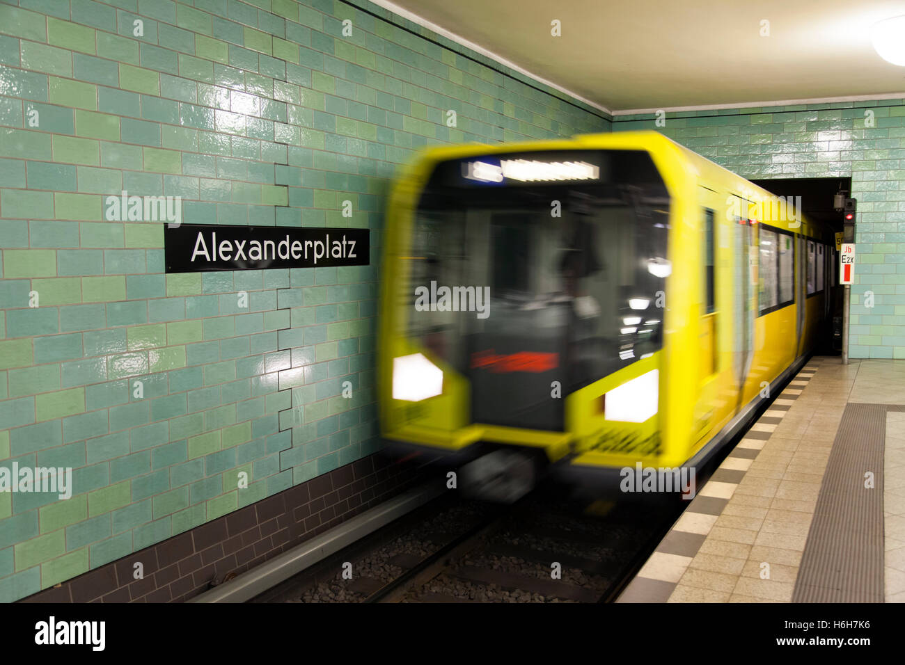 Sfocata motion view di un giallo treno arrivando alla piattaforma ad Alexanderplatz stazione della U-bahn a Berlino. Foto Stock