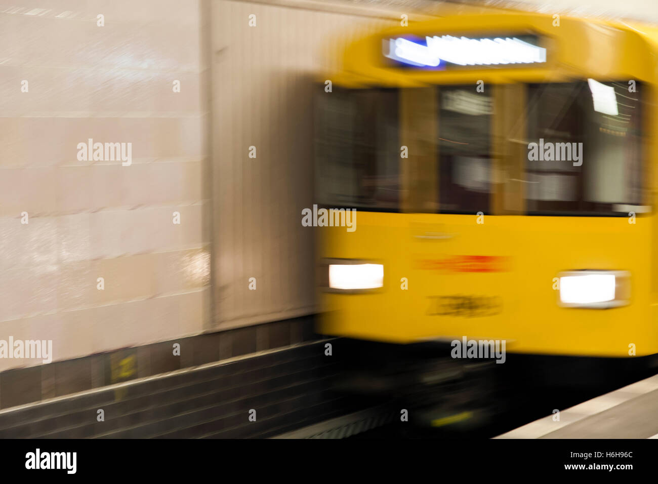 Sfocata motion view di un giallo U8 treno arrivando alla piattaforma in corrispondenza di una stazione della U-bahn a Berlino. Foto Stock