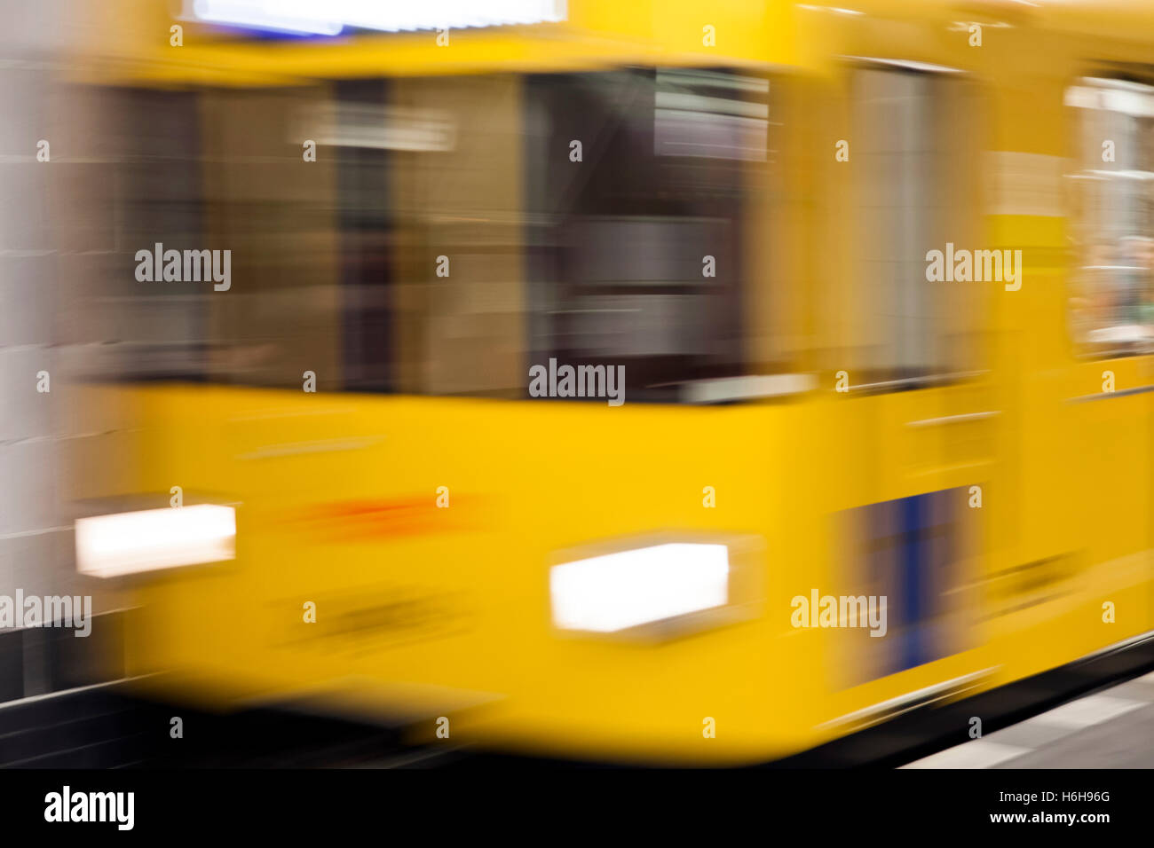 Sfocata motion view di un giallo U8 treno arrivando alla piattaforma in corrispondenza di una stazione della U-bahn a Berlino. Foto Stock