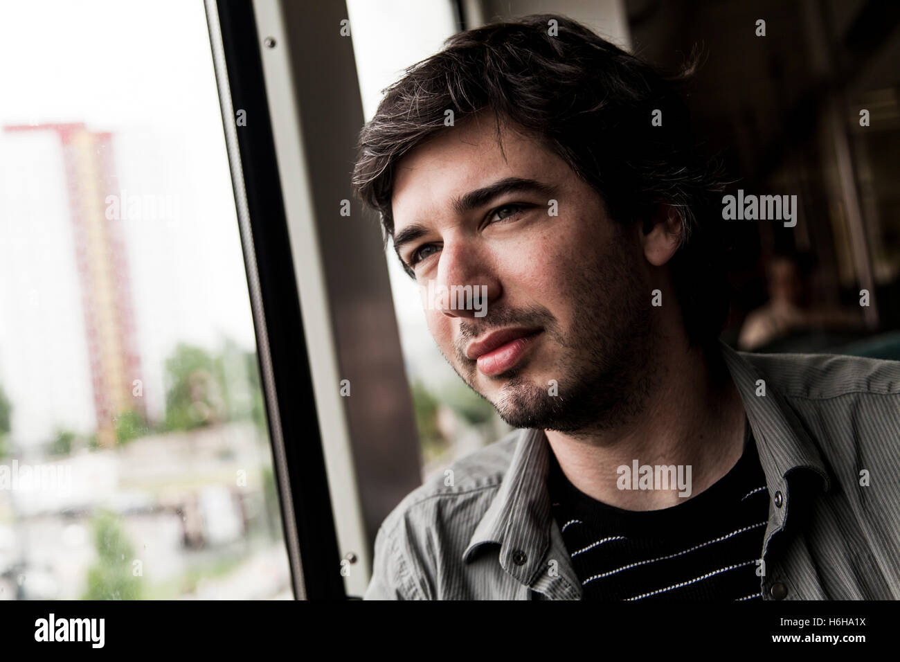 Ritratto di un uomo adulto nel suo 30s, guardando fuori dalla finestra del treno è a. Foto Stock