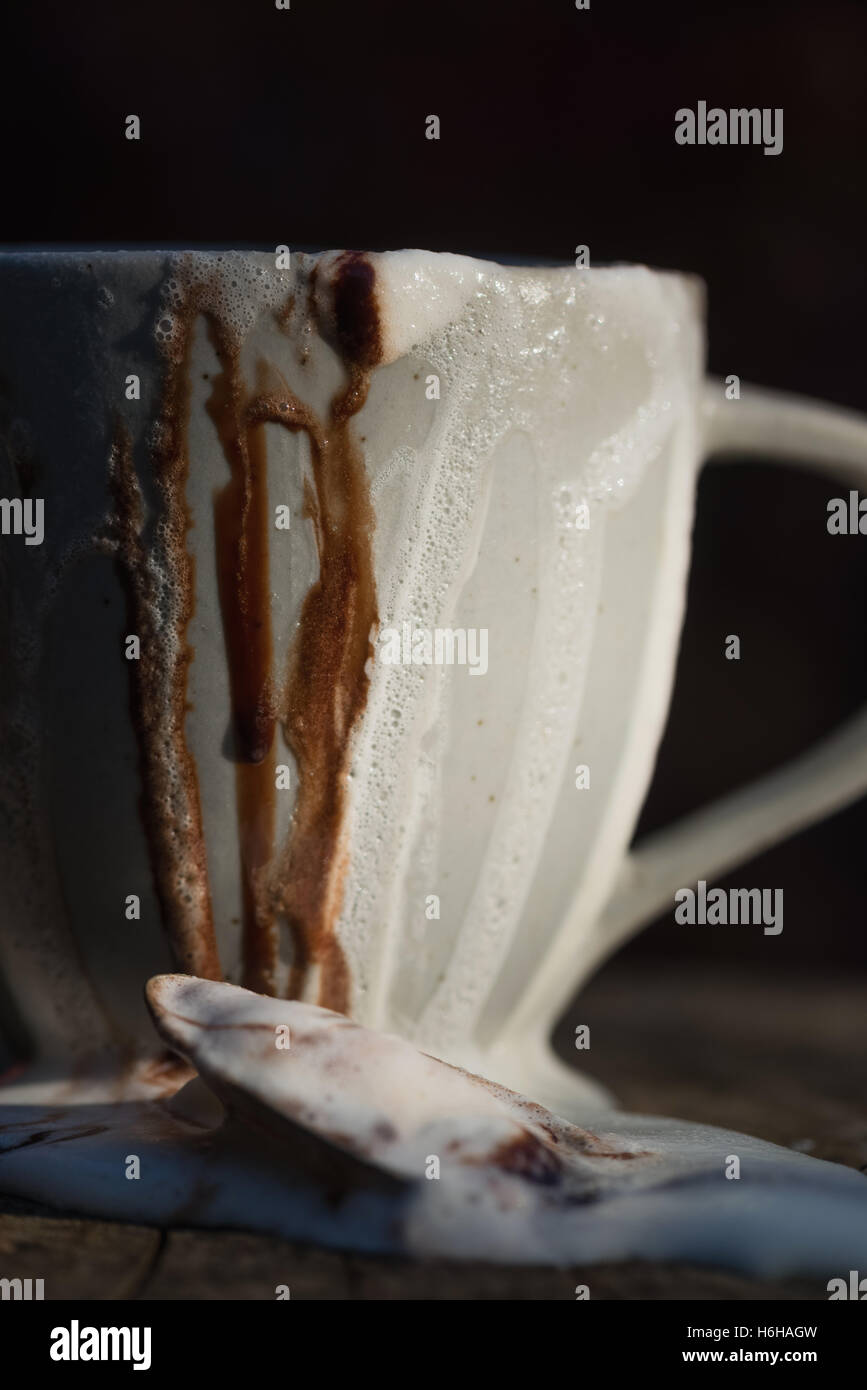 Molto disordinato di cioccolata calda con panna montata e salsa al cioccolato traboccante di una tazza alta impostata sul ceppo di albero Foto Stock Molto disordinato di cioccolata calda con panna montata e salsa al cioccolato traboccante di una tazza alta impostata sul ceppo di albero Foto Stock