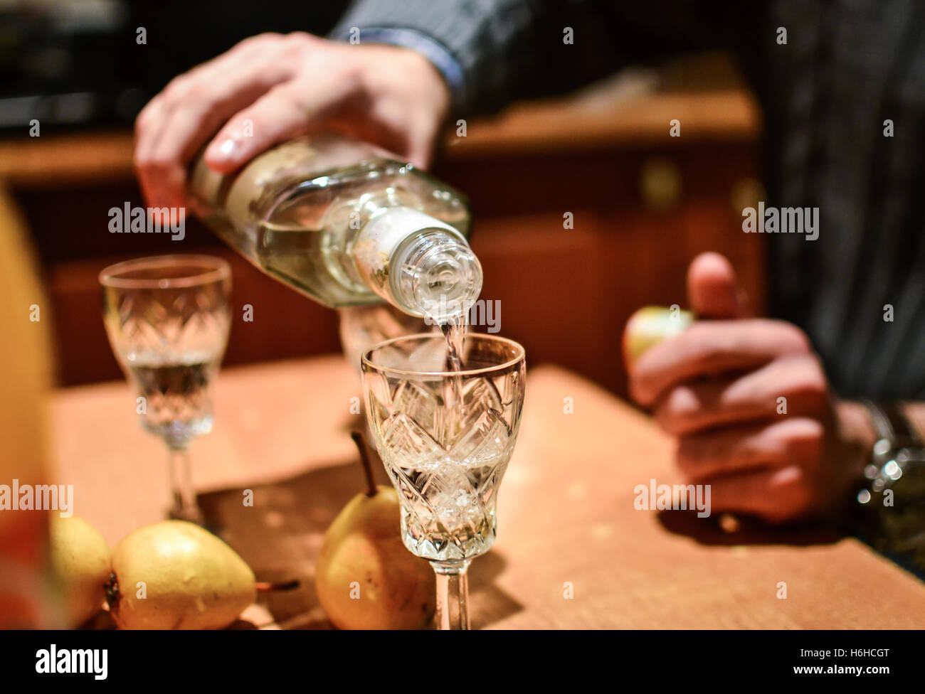 Uomo forte versare la bevanda alcolica vodka in vetro Foto Stock