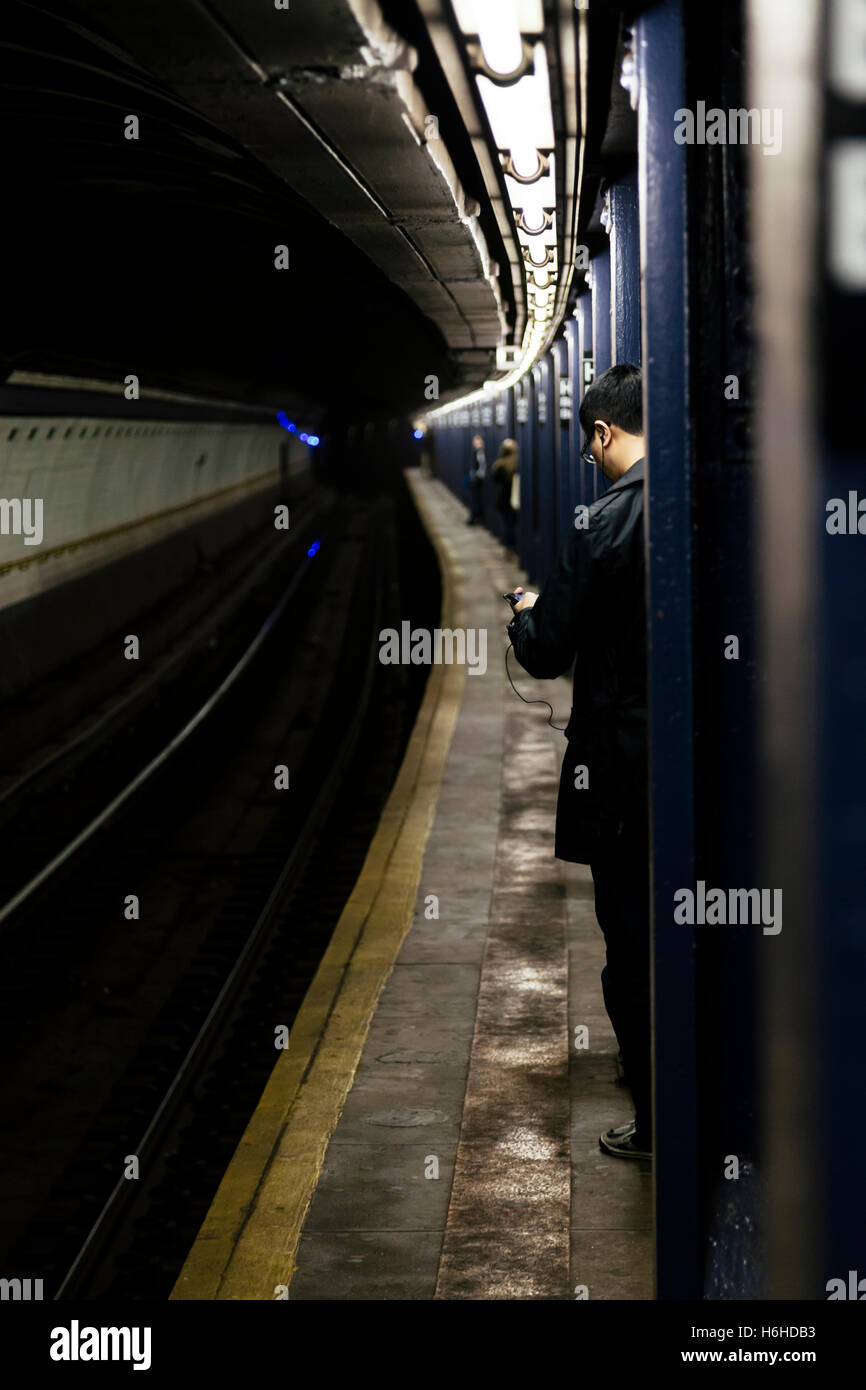 NEW-YORK - NOV 17: Uomo di attesa per il treno sulla piattaforma di una stazione della metropolitana a New York, Stati Uniti d'America il 17 novembre 2012. Foto Stock