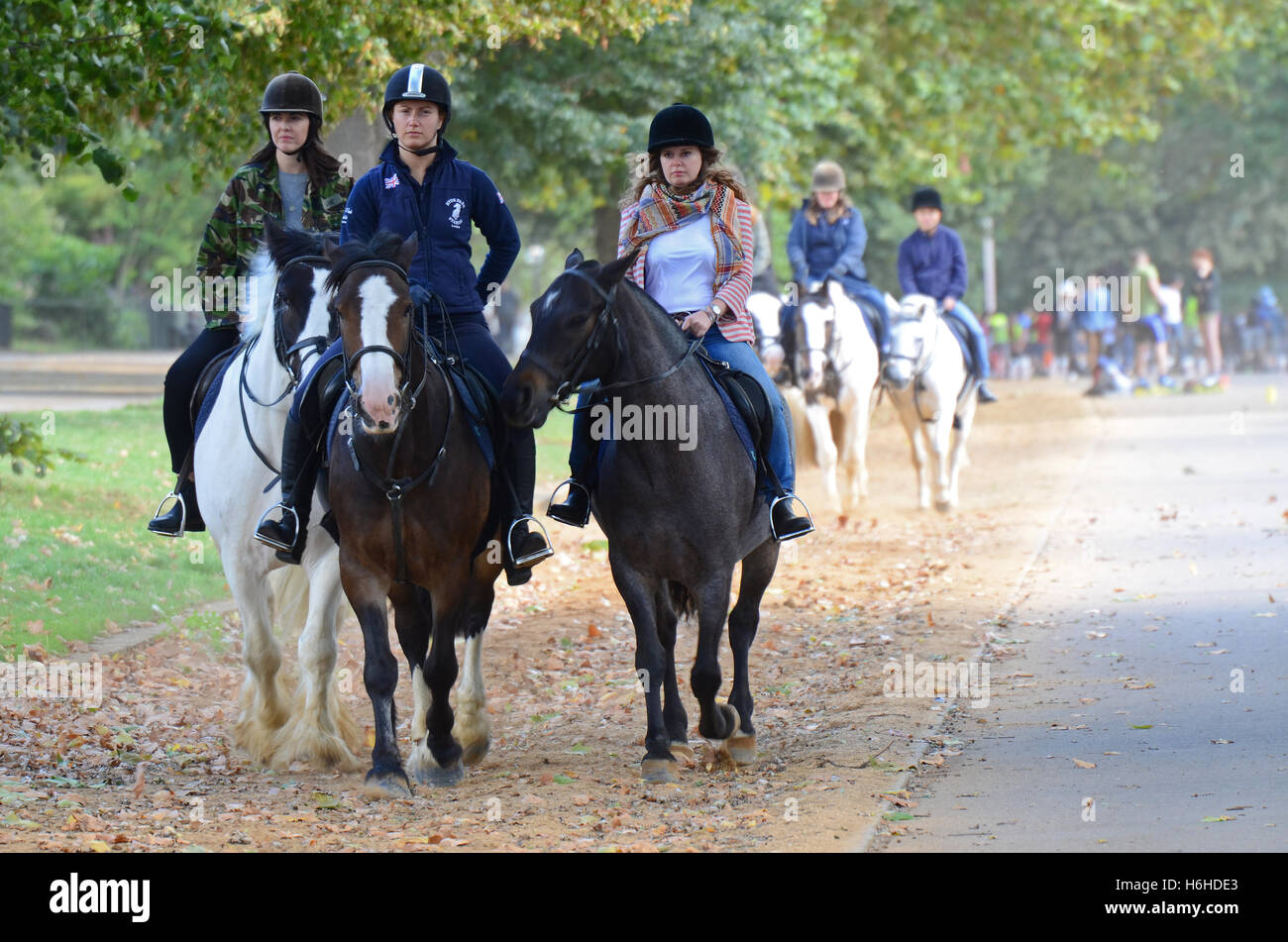 Horse Riding piloti attraverso Hyde Park accanto alla serpentina, mentre skateboarders anche fare uso del Parco Nazionale di spazio. Ambienti polverosi Foto Stock