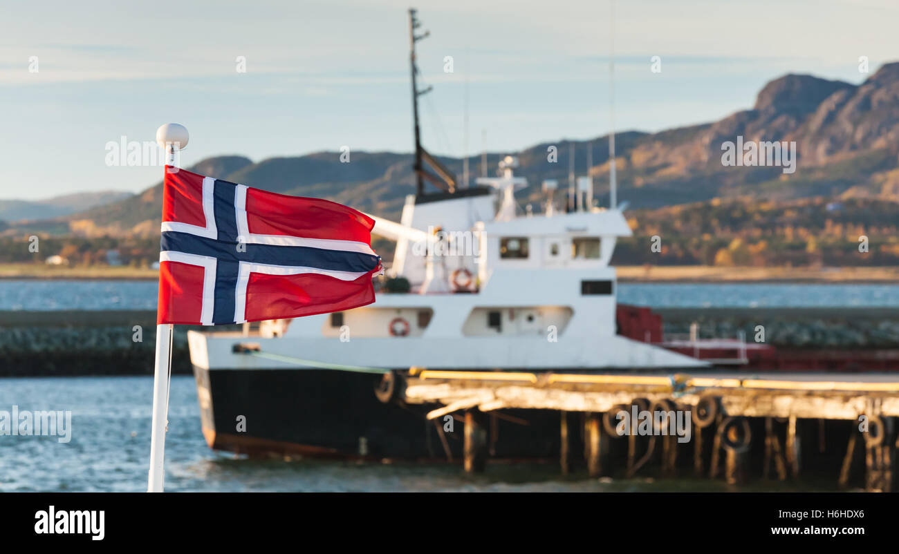 Bandiera norvegese sventolare su ringhiere della nave nel porto di Brekstad, Norvegia. Vintage foto stilizzata con calde tonalità Foto Stock
