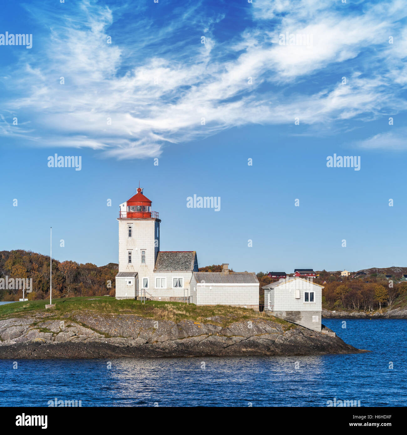 Faro Tyrhaug, torre bianca con la luce rossa sotto il cielo nuvoloso. Faro costiero situato nel comune di Smola, More og Romsd Foto Stock