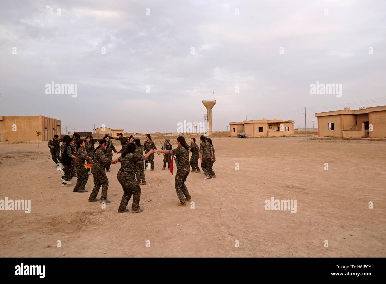 Combattenti curdi delle unità di protezione del popolo YPG e il Unità di protezione delle donne YPJ danza tradizionale curda danza in un Campo militare di al Hasakah o distretto di Hassakeh in Siria settentrionale Foto Stock