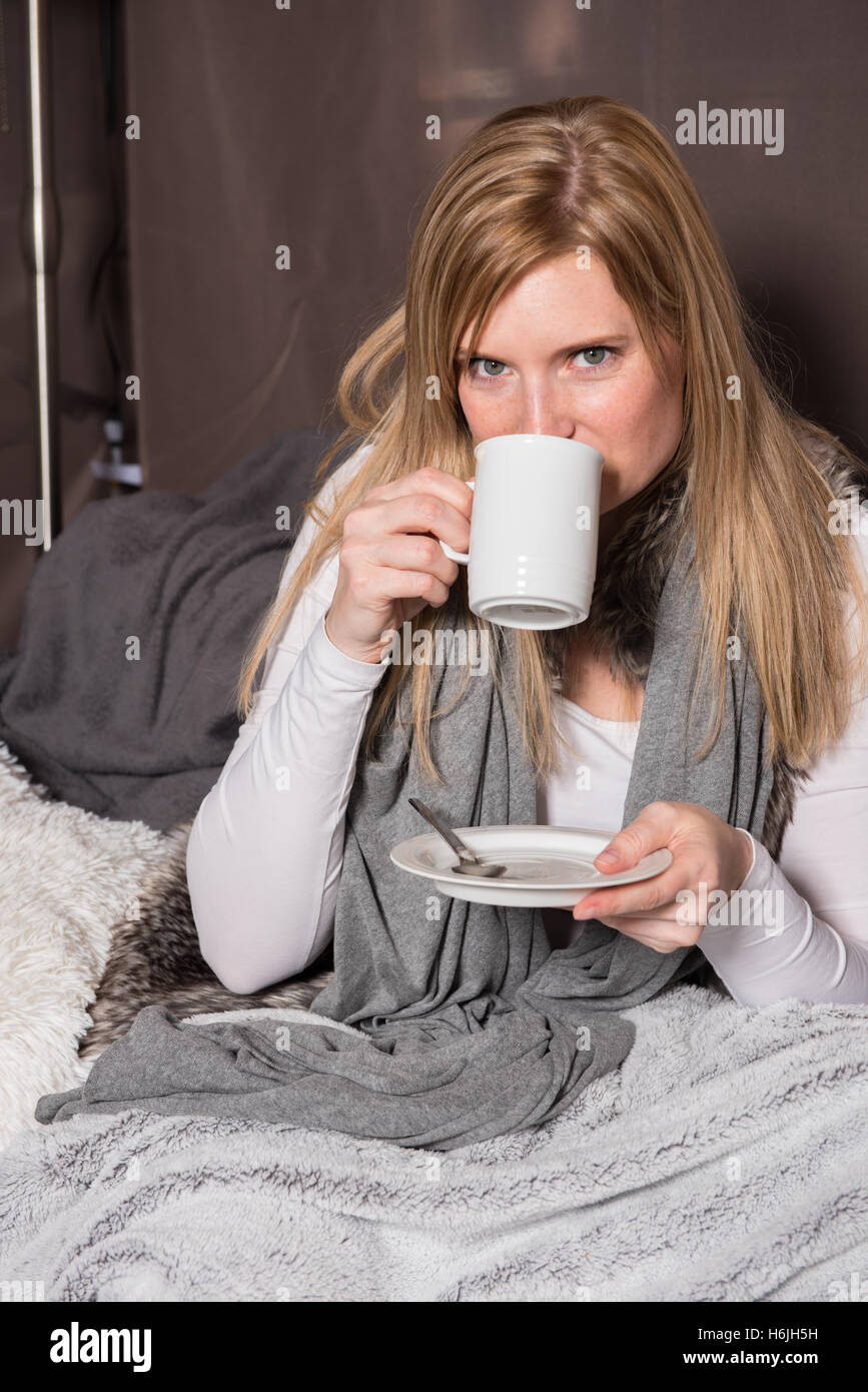 Donna attraente di bere la sua bevanda calda dalla tazza Foto Stock