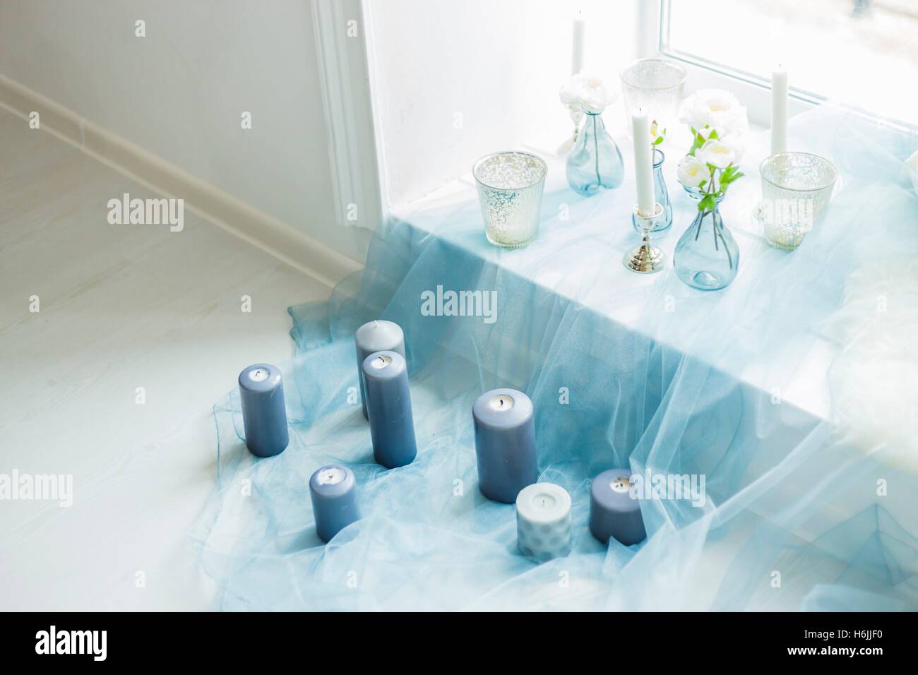 Il decor di photostudio - Candele grigio, bianco e cuscini di colore grigio, blu, tessili artificials fiori Foto Stock