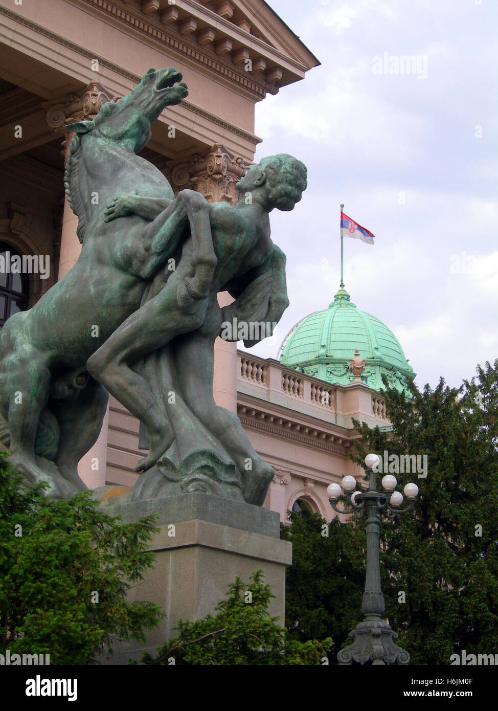 Statua monumento di uomo e cavallo entrata alla casa dell'Assemblea nazionale della Repubblica di Serbia il palazzo del Parlamento con la bandiera nazionale Belgra Foto Stock