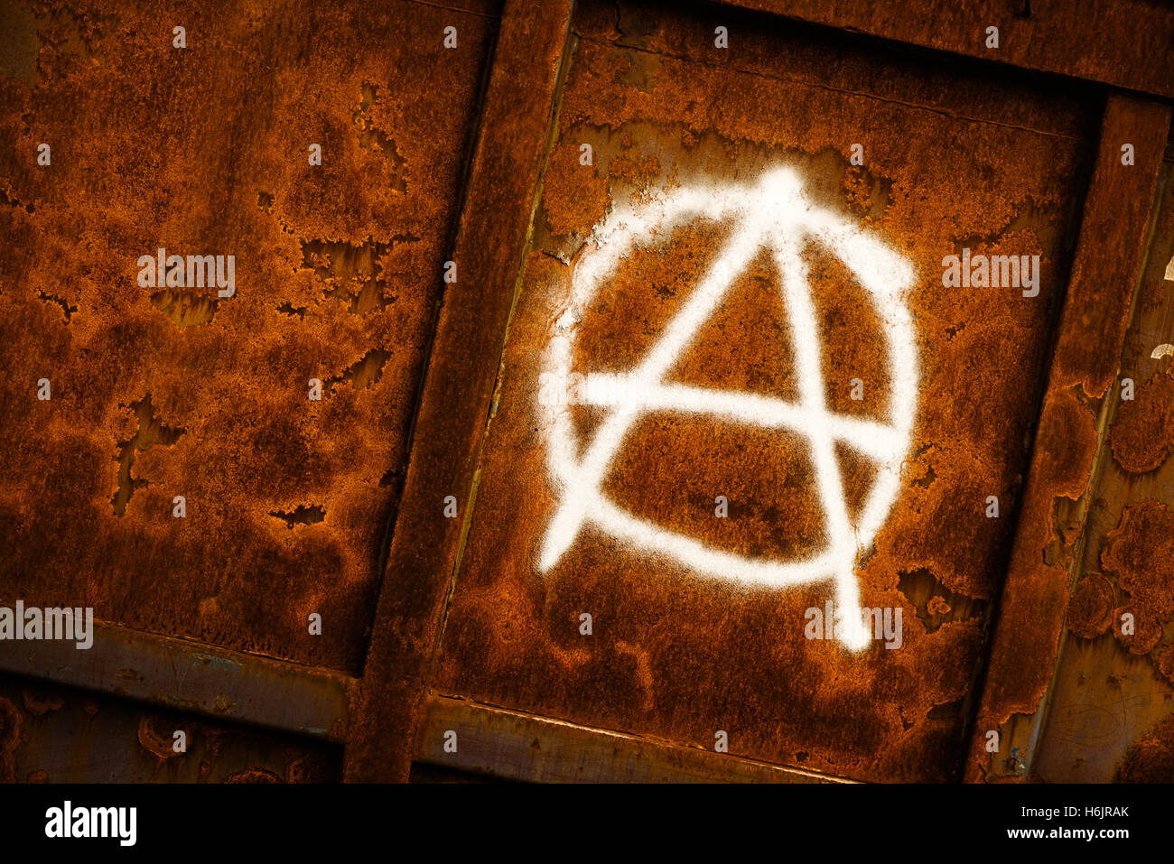 Anarchia simbolo graffiti verniciato a spruzzo su grunge corroso parete metallica Foto Stock