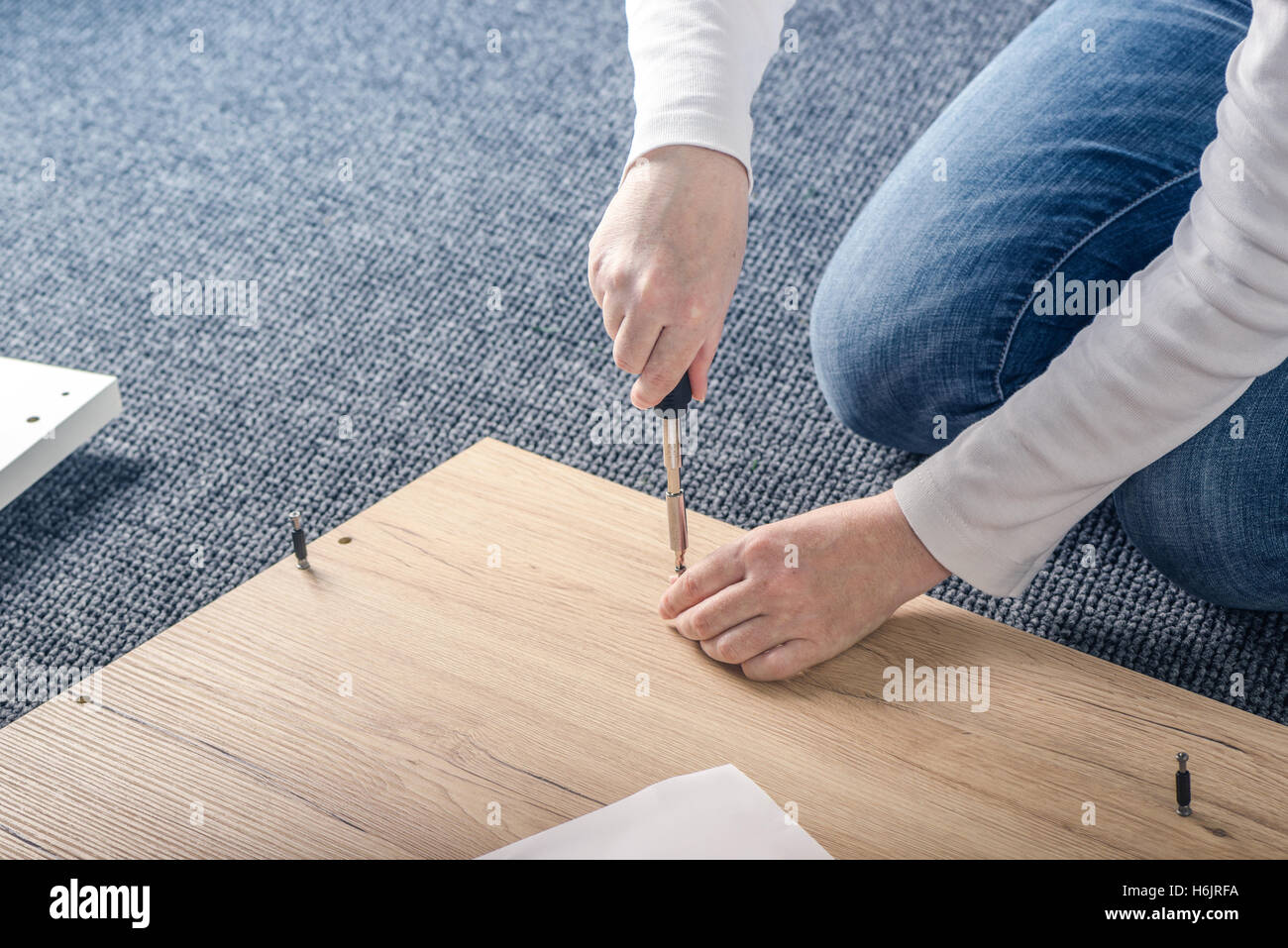 Donna di assemblaggio di mobili a casa sul pavimento, a mano con un cacciavite Foto Stock