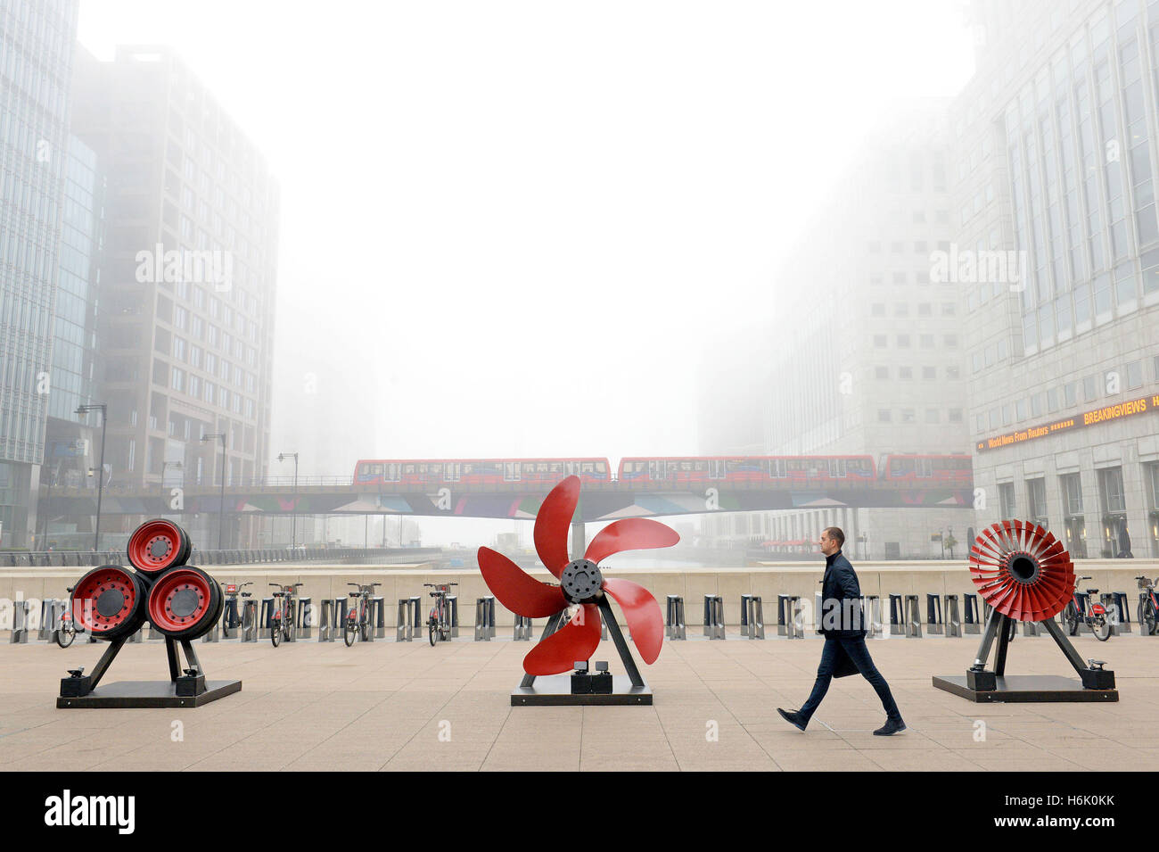 Un uomo cammina passato papaveri astratta che rappresenta l'esercito, la marina e la forza dell'aria dall'artista Marco Humphrey come parte del ricordo Art Trail a Canary Wharf, Londra. Foto Stock