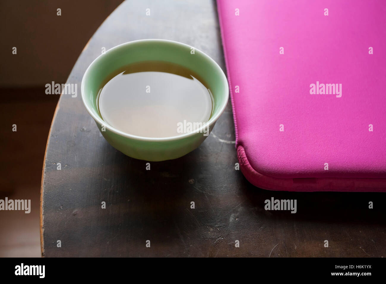 Il tè verde e Apple Mac Book Air nel caso rosa sulla tavola rotonda Foto Stock