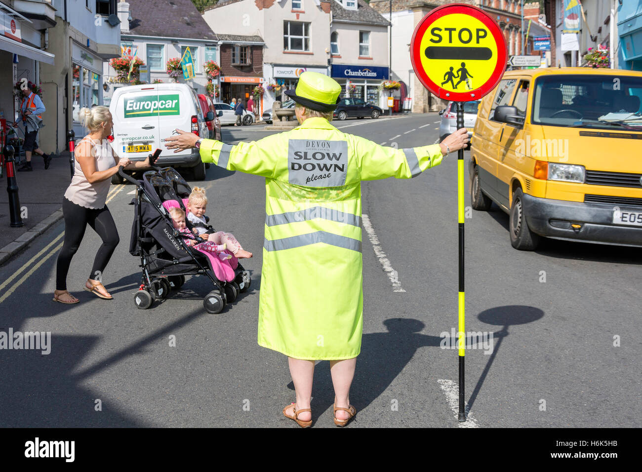 Lecca-lecca lady (attraversamento scuola ufficiale di pattuglia) arrestare il traffico su Fore Street, Bovey Tracey, Devon, Inghilterra, Regno Unito Foto Stock