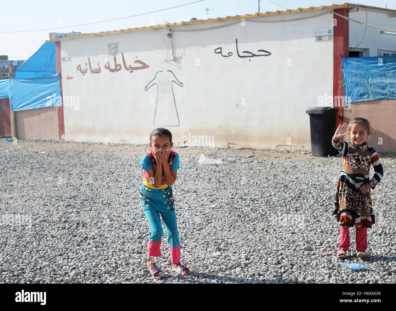 Due ragazze correre lungo un polveroso sentiero di ghiaia tra le sistemazioni in Debaga Refugee Camp tra Mosul e Erbil, Iraq, 18 ottobre 2016. Per i rifugiati delle Nazioni Unite organizzazione di aiuti si aspetta fino a un milione di rifugiati dalla lotta di Mosul. La Germania dovrà essere messa a 34 milioni di euro in aiuti immediati disponibili nella regione. Secondo l UNICEF, più di 500.000 bambini e le loro famiglie sarà un grande pericolo nelle prossime settimane a causa del recuperando della città di Mosul. In previsione di una ondata di profughi, materiali, soprattutto per la fornitura di acqua, vengono portati nella regione. Foto: Foto Stock