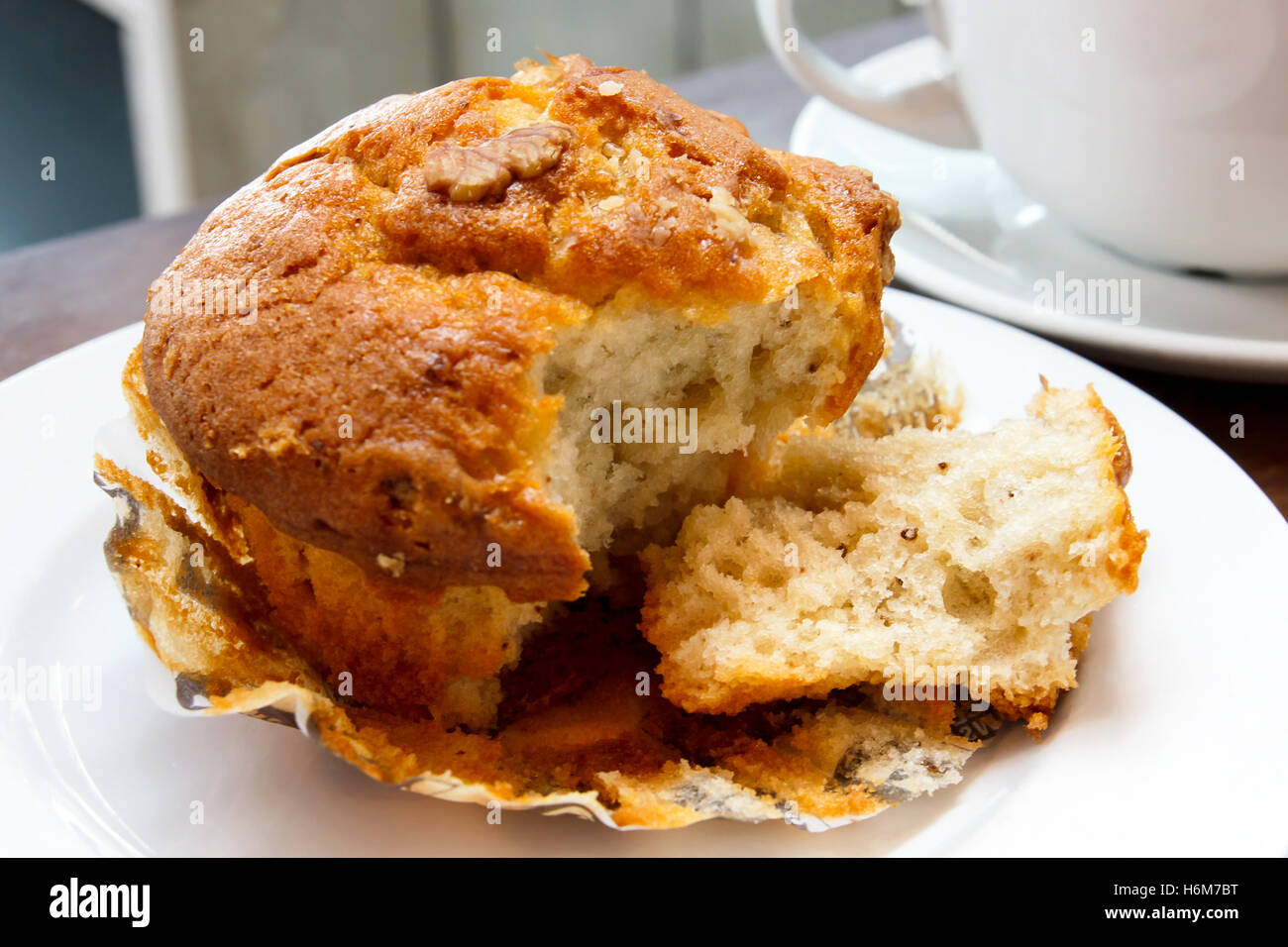 Primo piano della rotta muffin di noce su una piastra bianca in una caffetteria. Foto Stock