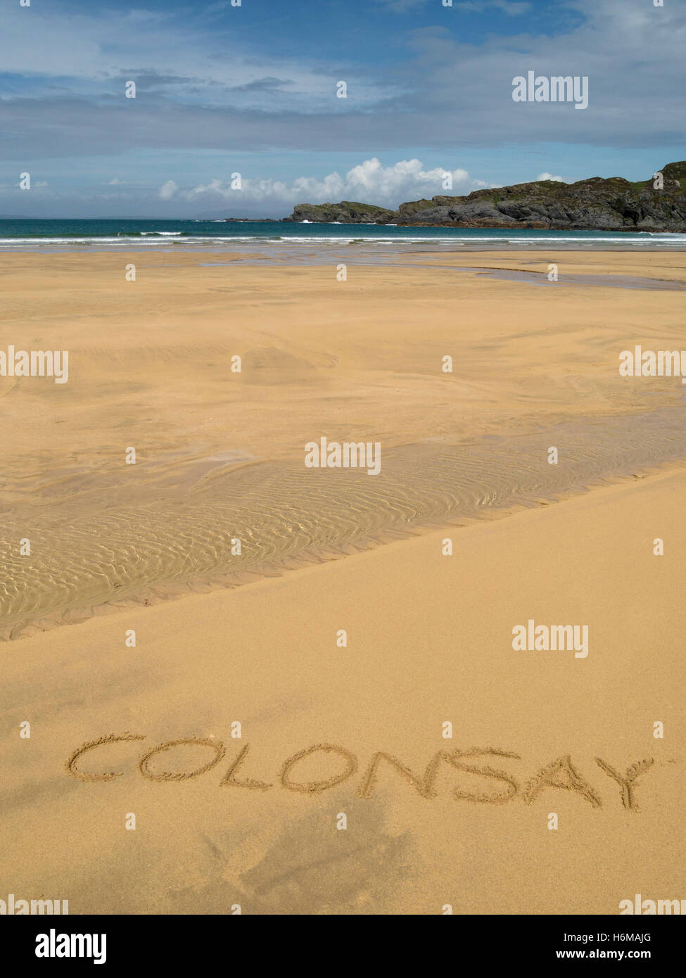 La parola "Colonsay' scritta in giallo dorato della sabbia Kiloran Bay Beach sull'isola remota di Colonsay, Scotland, Regno Unito. Foto Stock