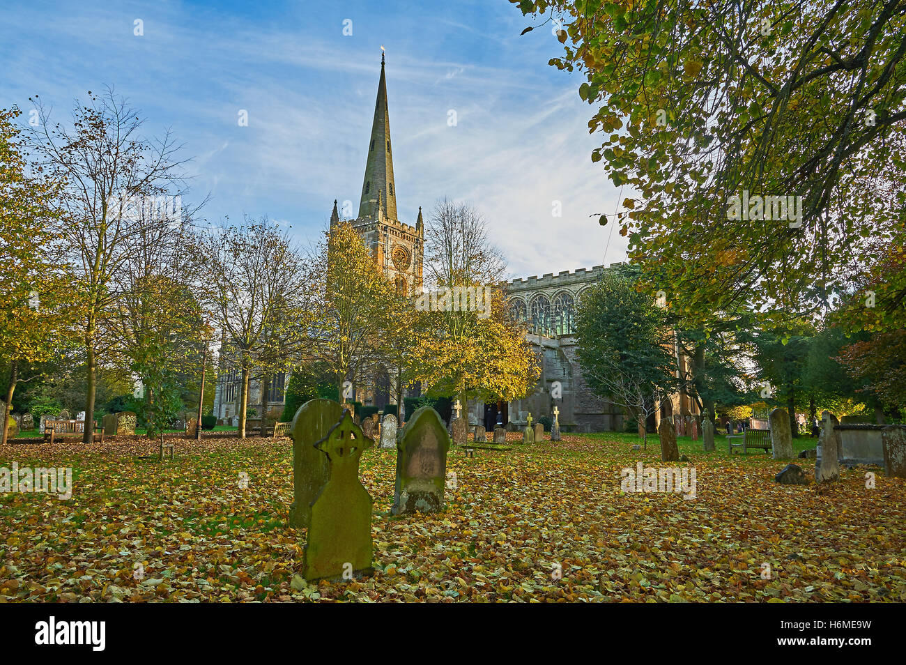 Foglie di autunno cadono attraverso il cortile della chiesa della chiesa della Santa Trinità, Stratford upon Avon, luogo di sepoltura di William Shakespeare. Foto Stock