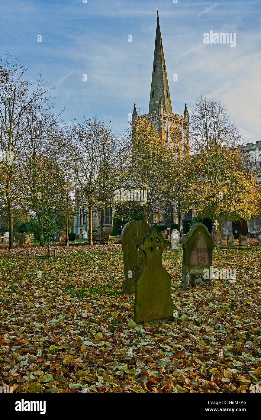 Foglie di autunno cadono attraverso il cortile della chiesa della chiesa della Santa Trinità, Stratford upon Avon, luogo di sepoltura di William Shakespeare. Foto Stock