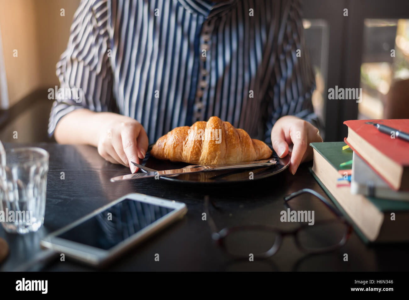 Fine settimana pomeriggio stile di vita e di attività della giovane donna parigamba lavoratore mangiare croissant sulla tavola di legno al cafe'. Domenica mattina li Foto Stock
