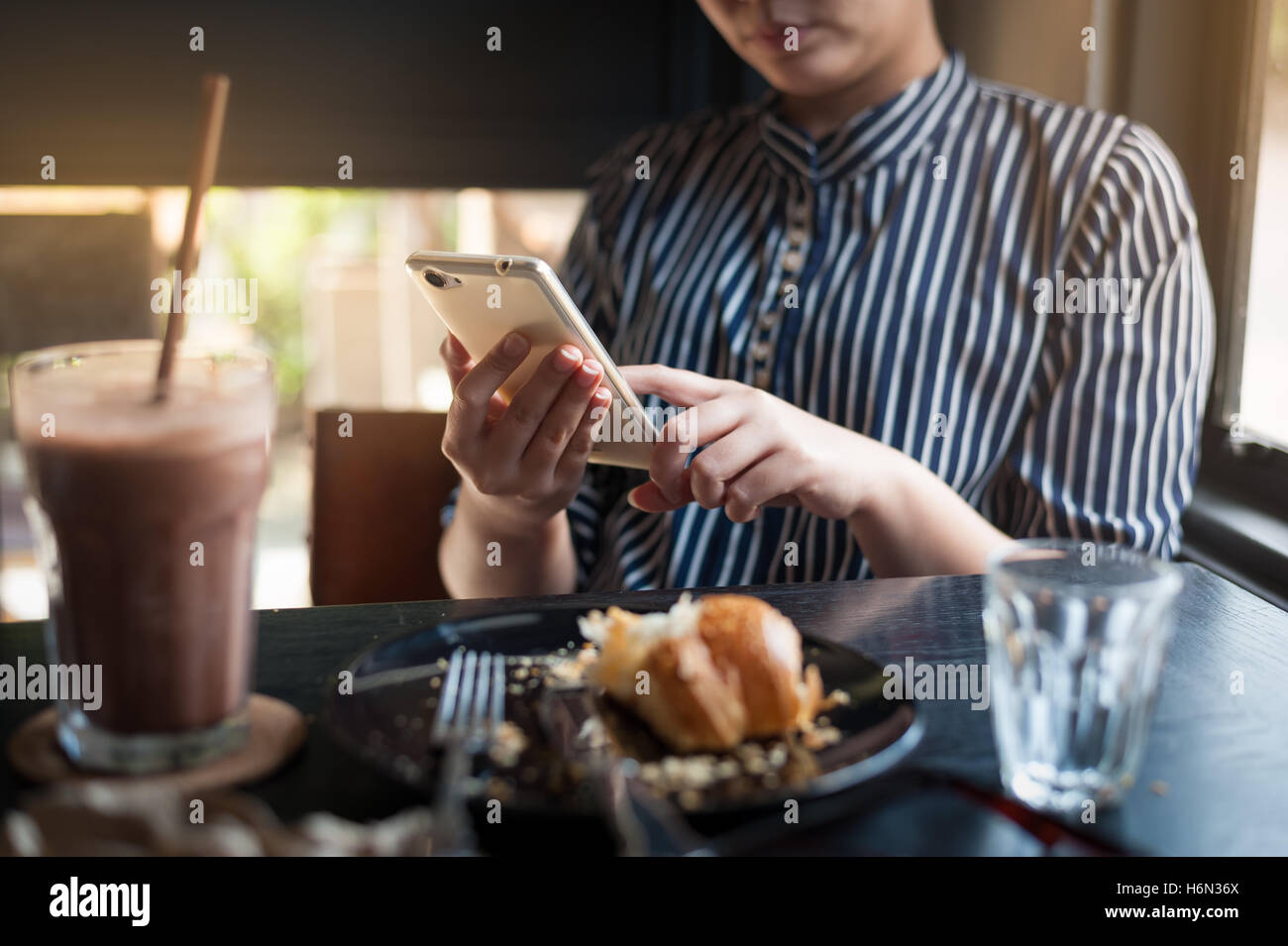 Domenica mattina scena dello stile di vita dei giovani hipster donna utilizzando il telefono cellulare mentre è seduto al cafe'. Stile di vita trendy sul weekend con Foto Stock