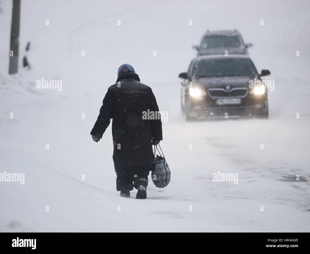 Kryvyi Rih, Ucraina - Gennaio, 18, 2016: vecchia donna indigenti nella vecchia pelliccia con shopping bag vagare lungo la strada snowbound, t Foto Stock