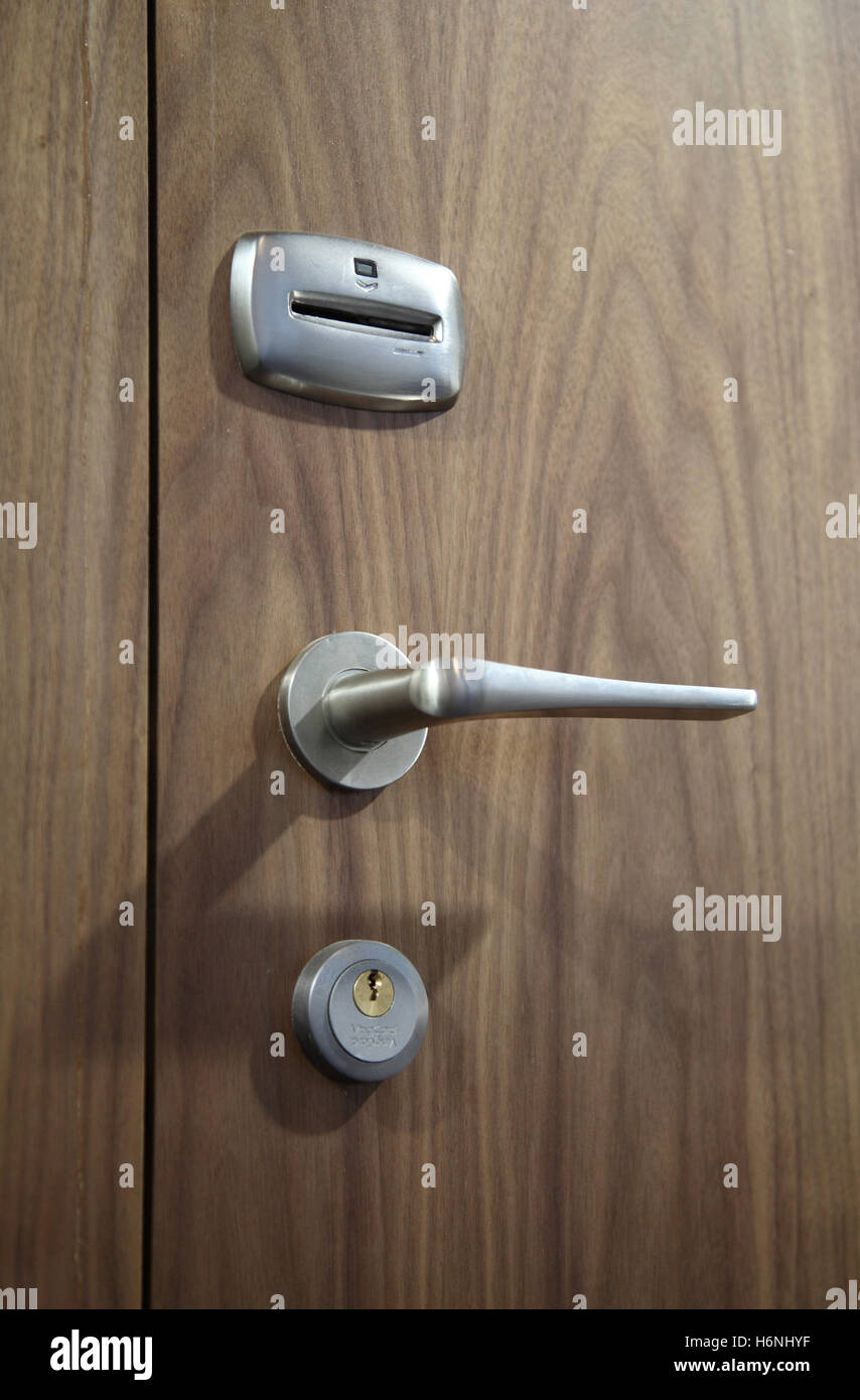 Dettaglio della maniglia della porta e la serratura della scheda su un hotel contemporaneo porta. Noce americano finitura in legno per porta. Foto Stock