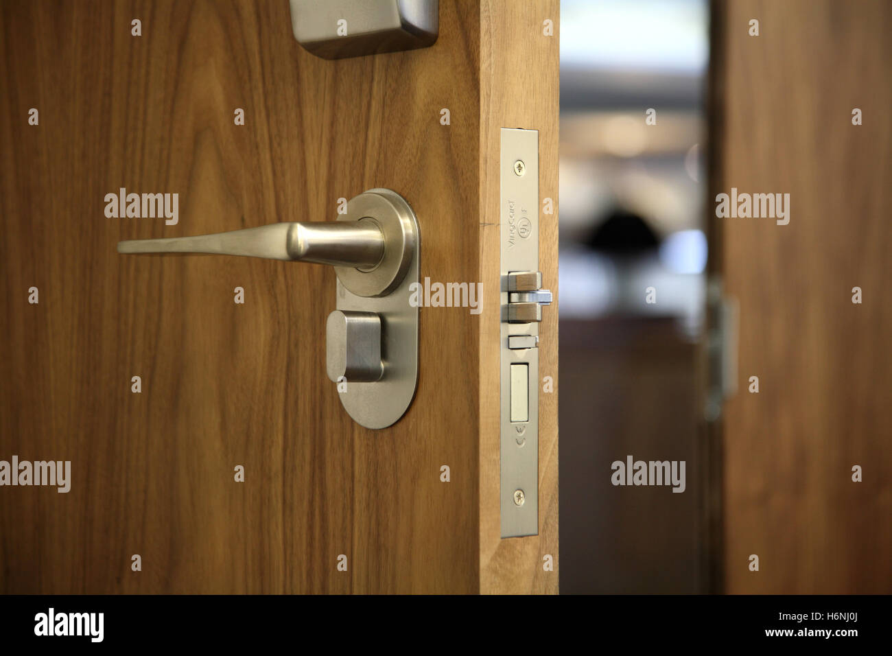 Dettaglio della maniglia della porta e la serratura della scheda su un hotel contemporaneo porta. Noce americano finitura in legno per porta. Foto Stock