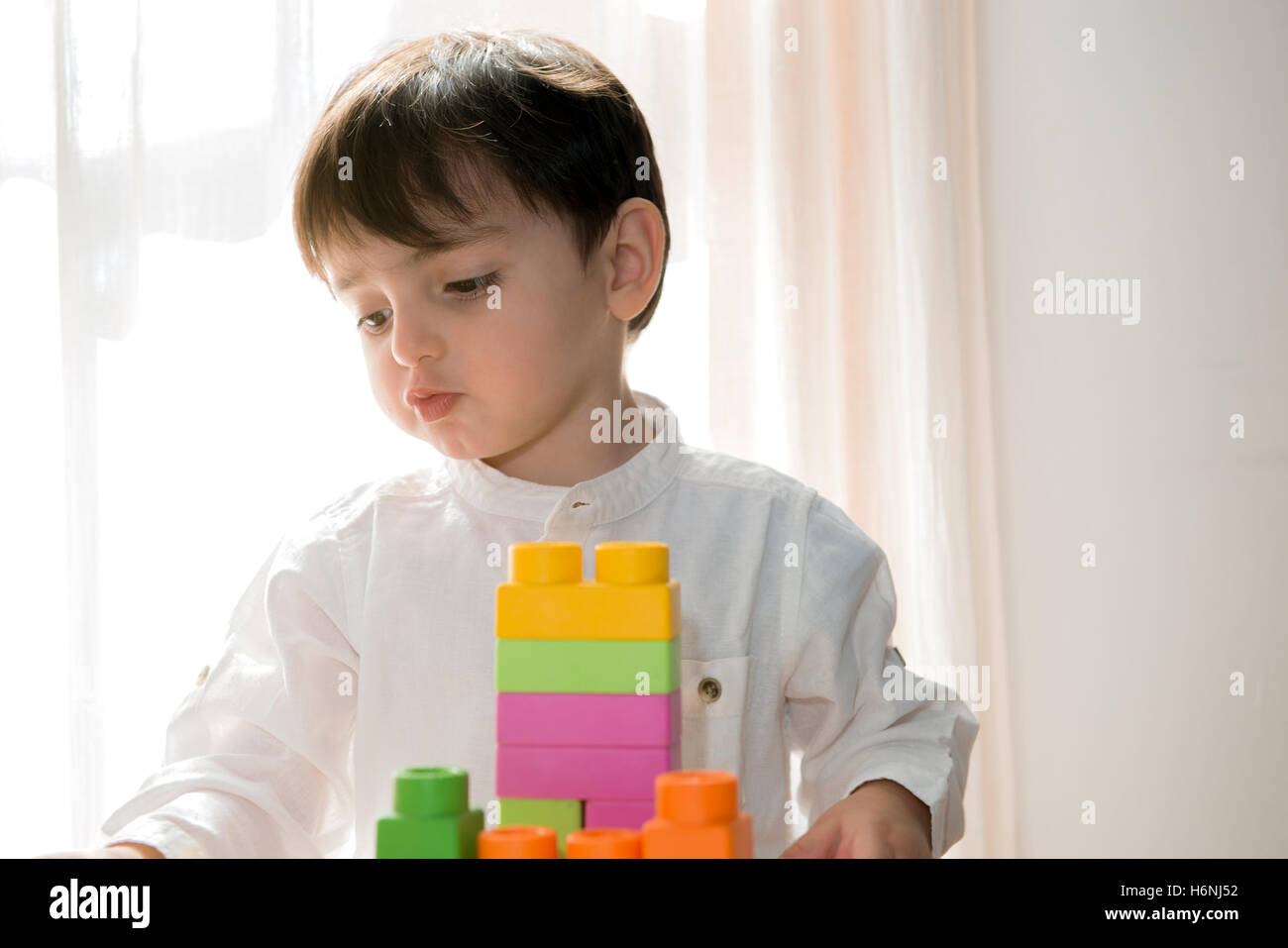Bambini che giocano con colorati mattoni in plastica Toddler divertendosi e costruire al di fuori del costruttore luminoso mattoni apprendimento precoce Foto Stock