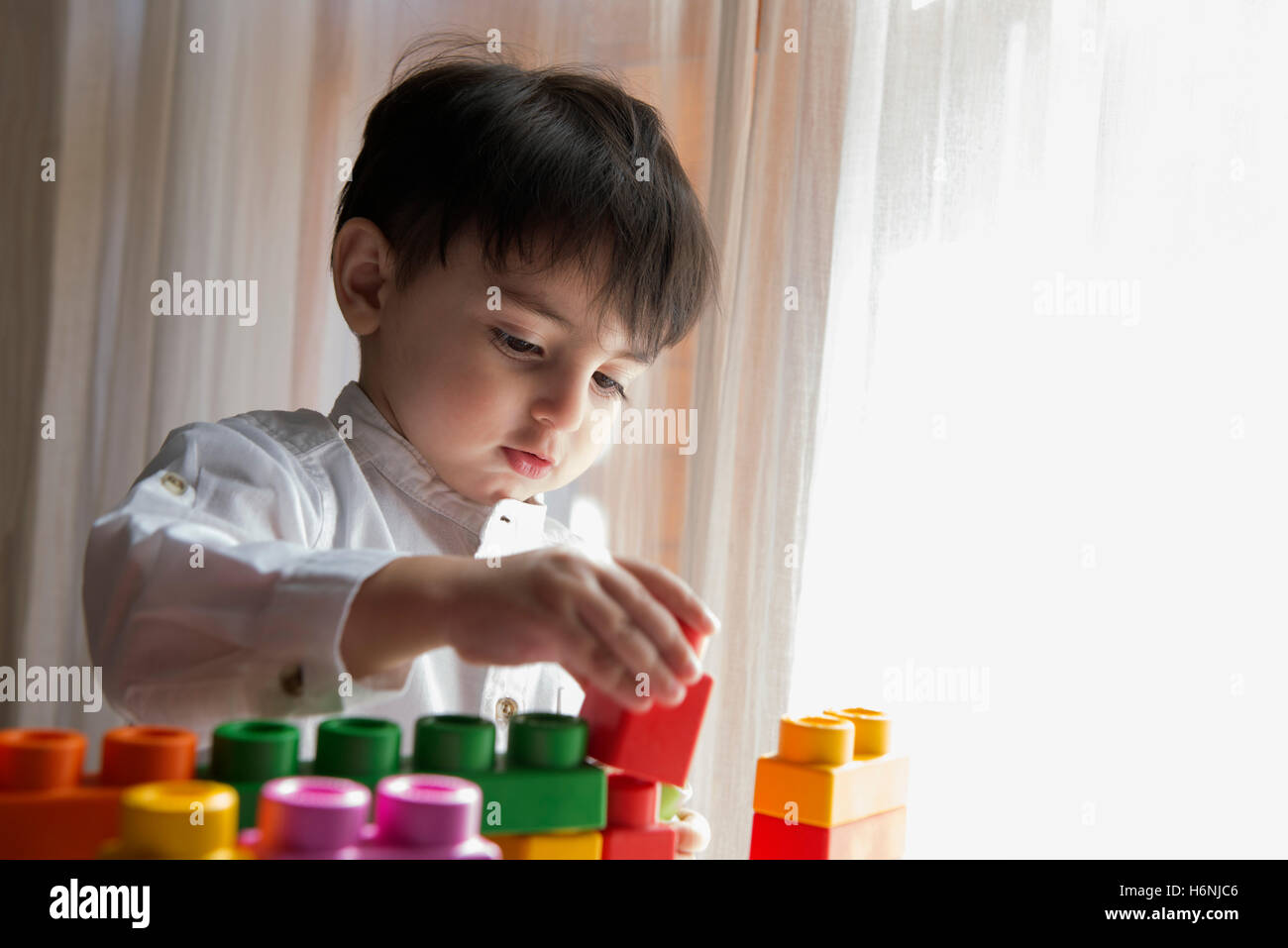 Bambini che giocano con colorati mattoni in plastica Toddler divertendosi e costruire al di fuori del costruttore luminoso mattoni apprendimento precoce Foto Stock