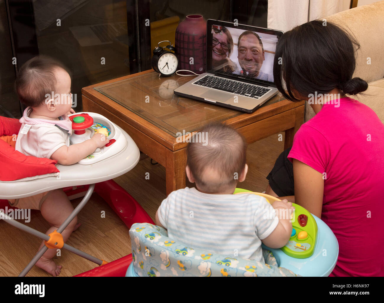 Twin neonati e madre guardando i nonni su Skype sul computer portatile Foto Stock
