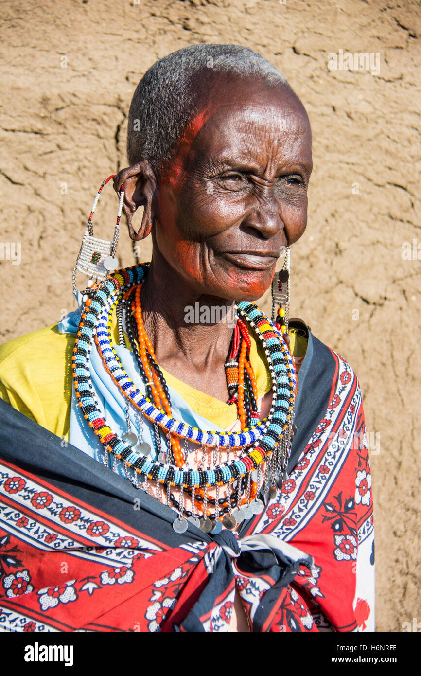 Anziana donna Masai con orecchioni stirata, indossando il tradizionale abito nativo, in un villaggio vicino al Masai Mara, Kenya, Africa Foto Stock
