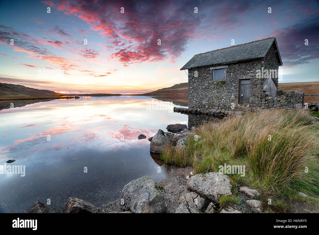 Tramonto su un vecchio boathouse in pietra sulle rive del Devoke acqua, un lago remoto su Birker cadde nel Lake District National par Foto Stock