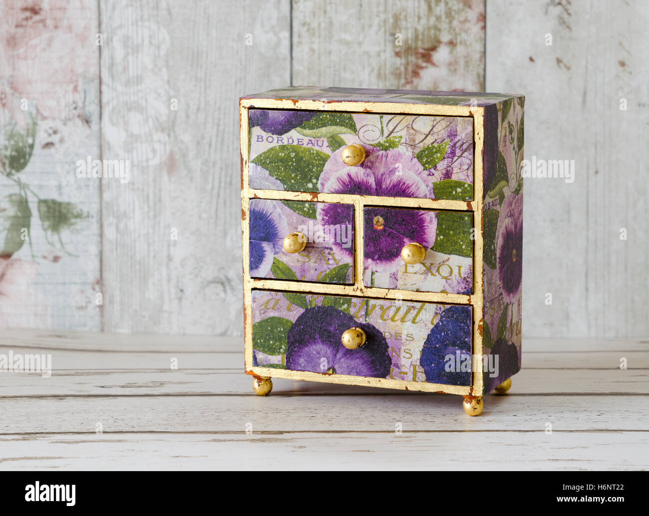 Un handmade mini cassettiera decoupaged in carte vintage e dorata con foglia oro Foto Stock