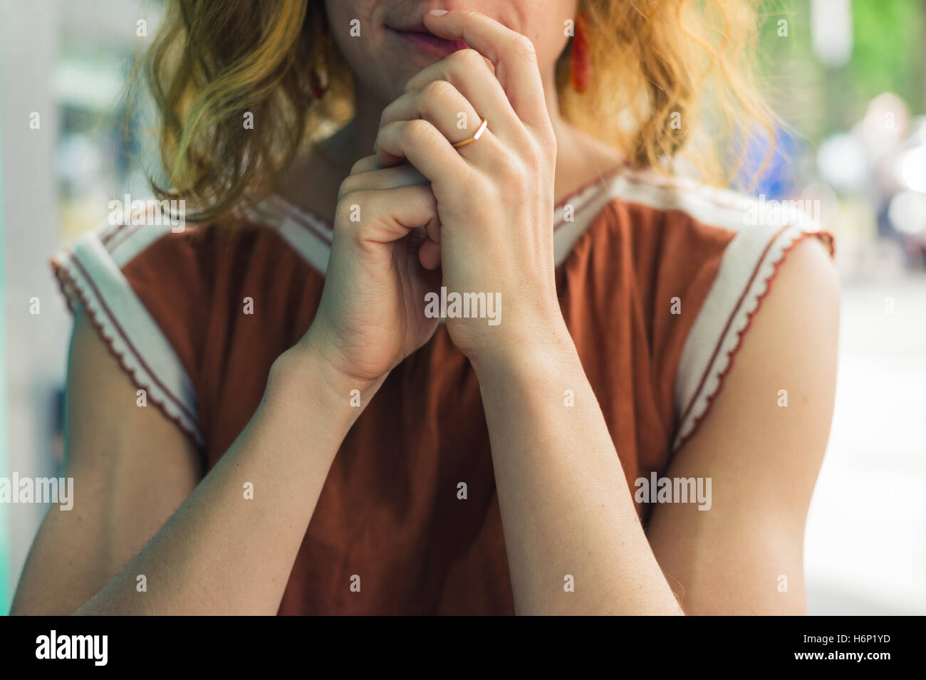 Una giovane donna è seduta al di fuori con le sue dita sulle labbra Foto Stock