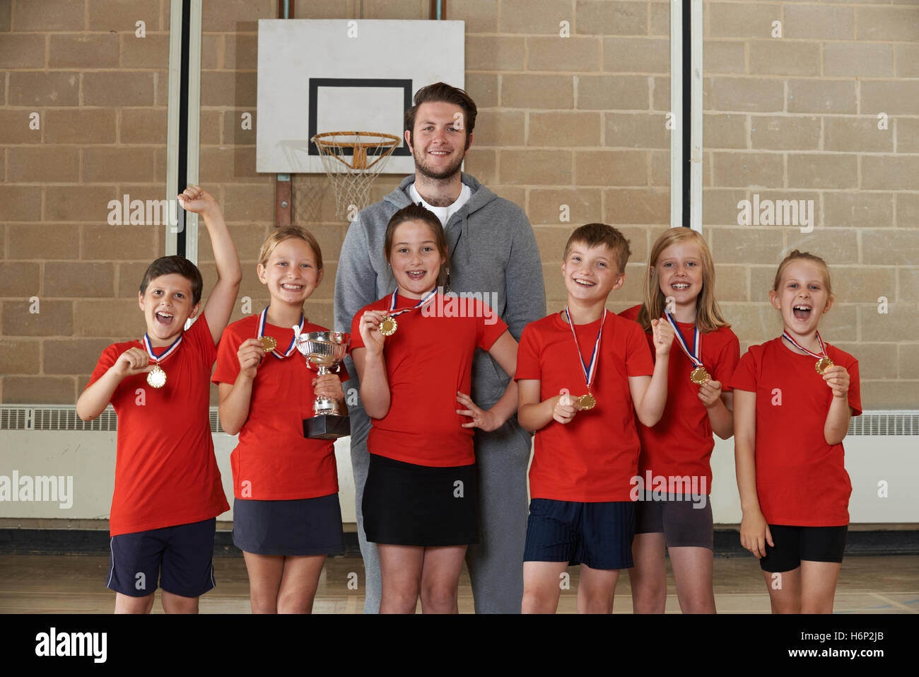 Vittoriosa Scuola di Sport Team con medaglie e Trofeo in palestra Foto Stock