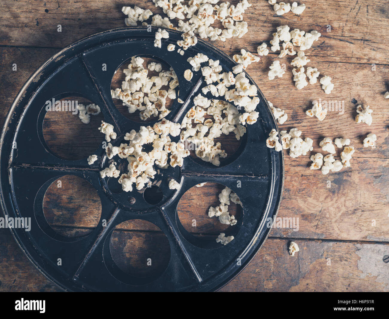 Concetto di Cinema vintage di bobina di pellicola con popcorn su una superficie di legno Foto Stock