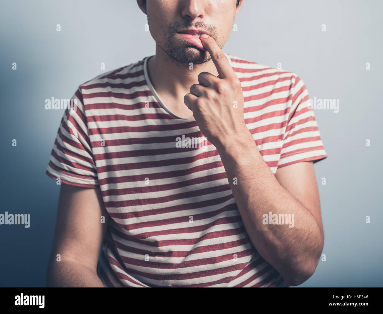 Un giovane uomo ha un mal di denti e viene a contatto con la sua bocca Foto Stock