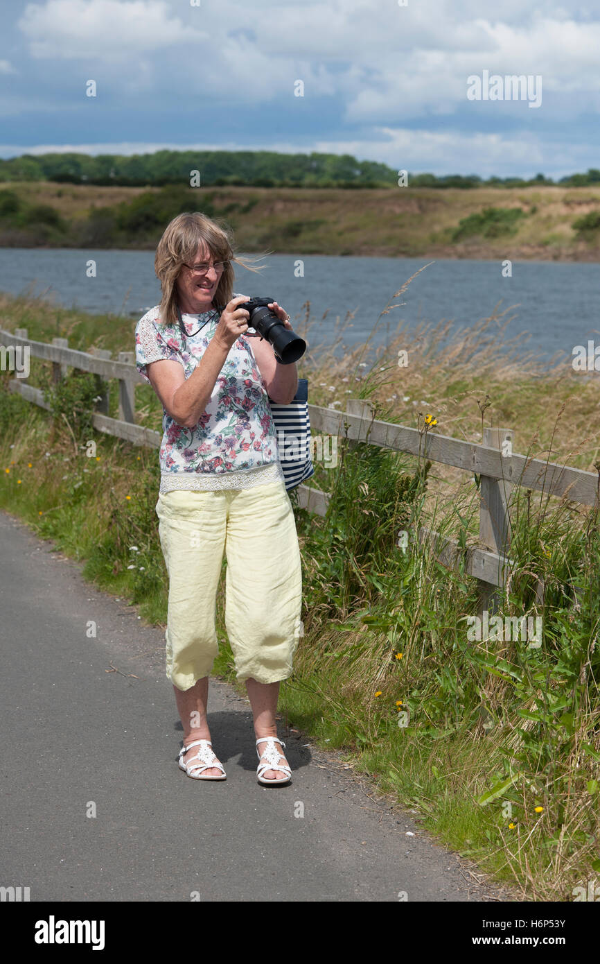 Femmina adulta fotografo controllo immagine sulla fotocamera digitale. Foto Stock