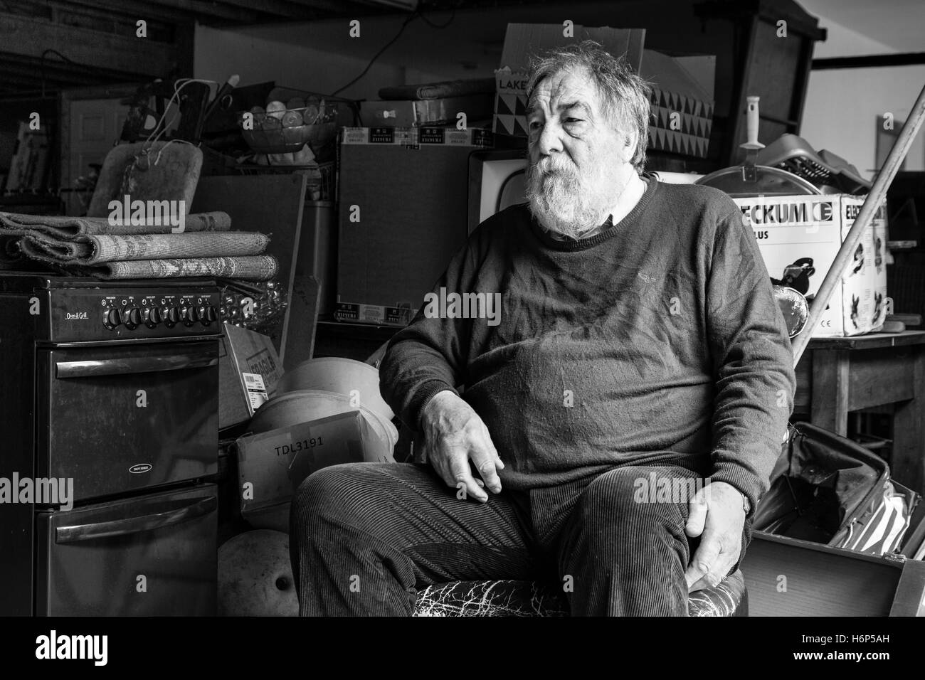 Vecchio Uomo seduto in una vecchia sedia nel suo negozio di posta indesiderata. Cahersiveen, nella contea di Kerry, Irlanda. Foto Stock