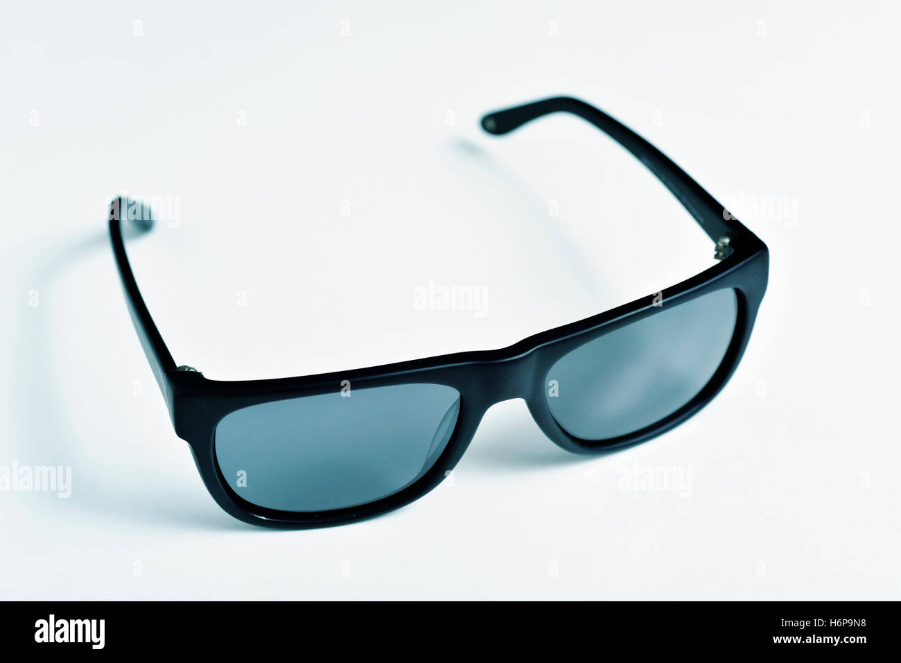 Primo piano di una coppia di plastica nera bordata di occhiali da sole su una superficie bianca Foto Stock