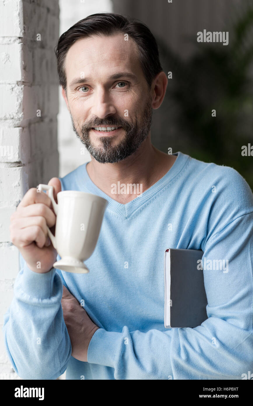 Positivo uomo allegro tenendo il piacere nella sua rottura Foto Stock