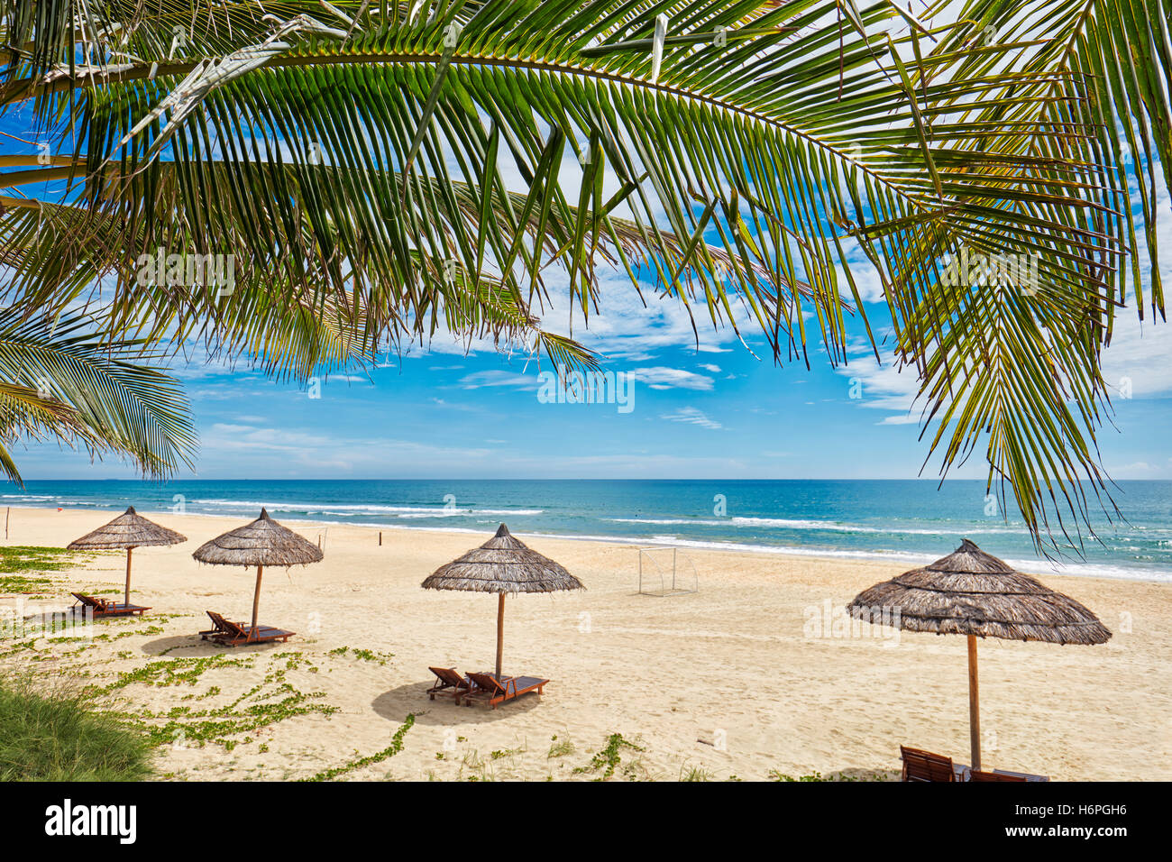 Sedie a sdraio sotto gli ombrelloni di paglia su Lang Co Beach. Thua Thien Huê Provincia, Vietnam. Foto Stock