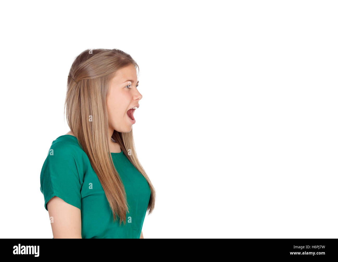 Bella ragazza giovane con la maglietta verde urlando a tutto volume isolato su sfondo bianco Foto Stock