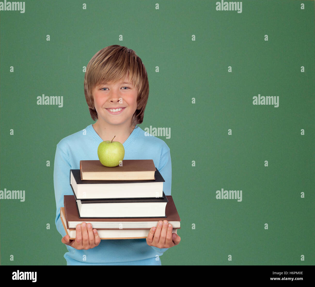 Preteen boy con molti libri con una lavagna verde per backgrond Foto Stock