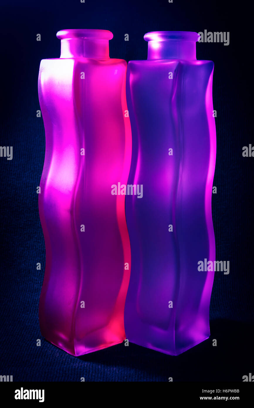 Close-up di due ondulati viola e rosa in vetro smerigliato vasi contro uno sfondo scuro Foto Stock