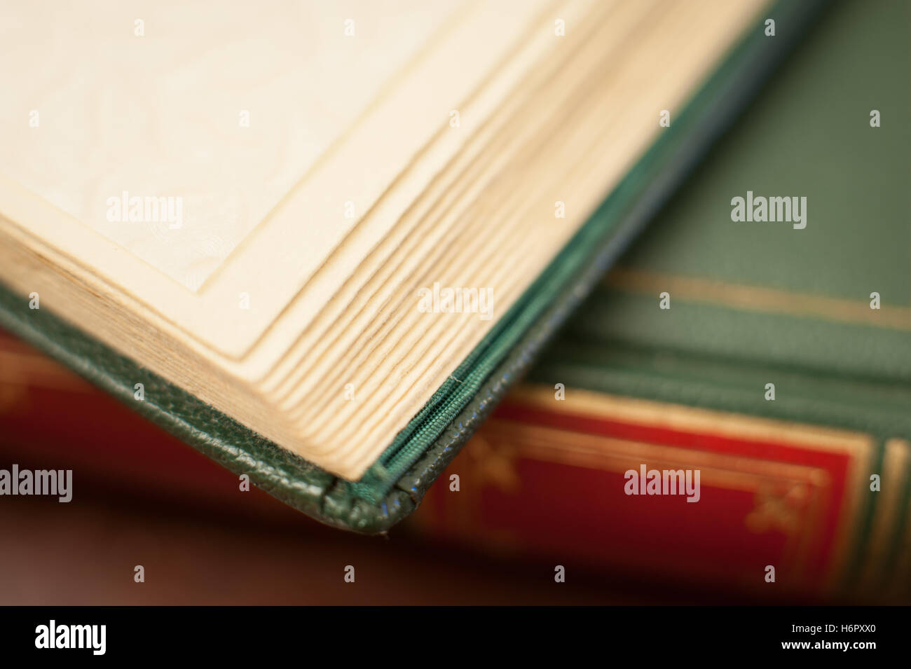 Antico libro rosso e verde angolo di copertura dettaglio, concentrarsi su aprire pagine vuote Foto Stock