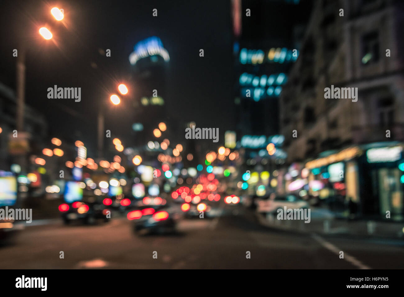 Sfocato incandescente grattacieli e automobili. La città di notte le luci di strada sullo sfondo Foto Stock