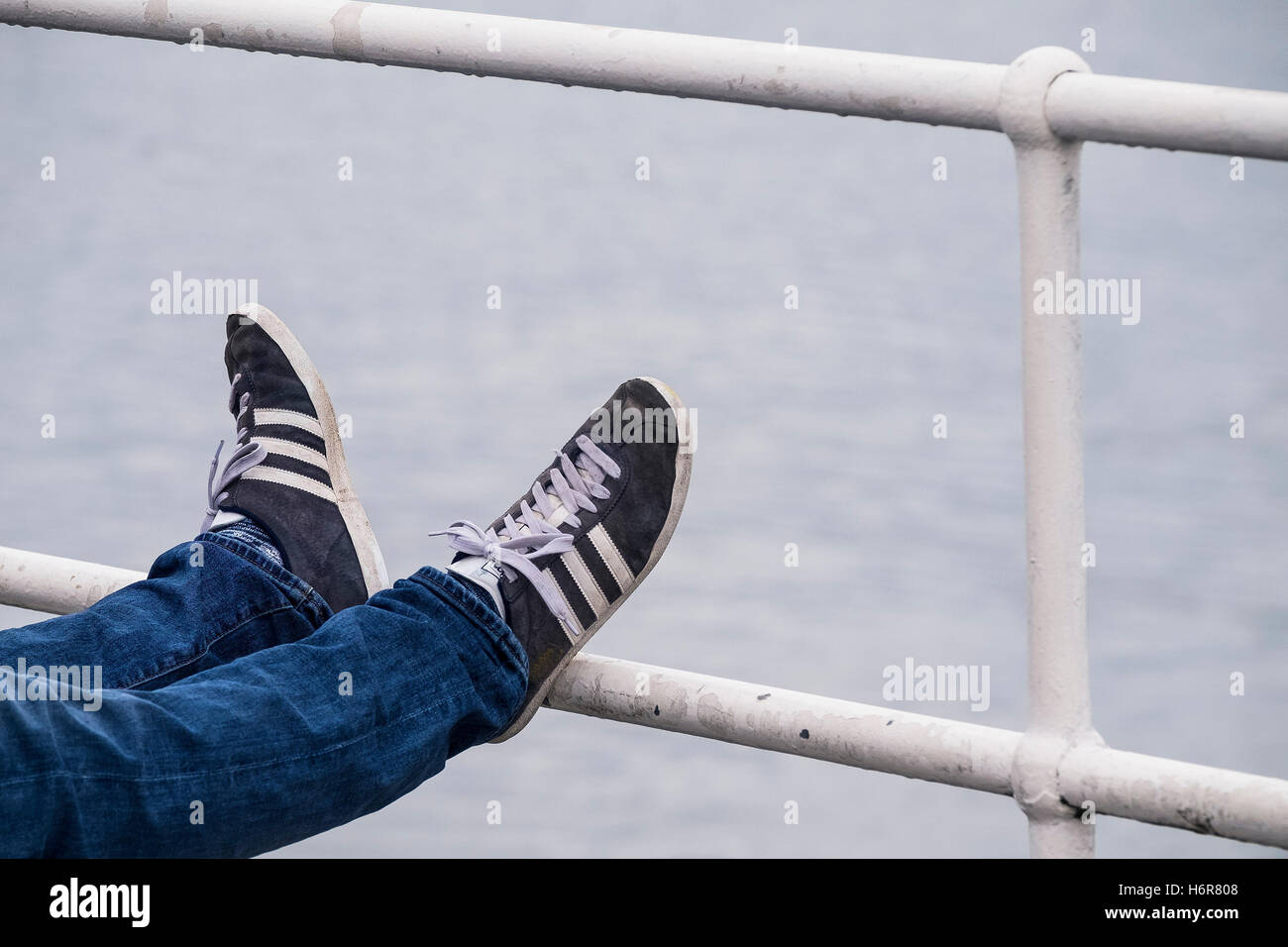 Un turista si rilassa con i piedi sulla ringhiera in Falmouth, Cornwall. Foto Stock
